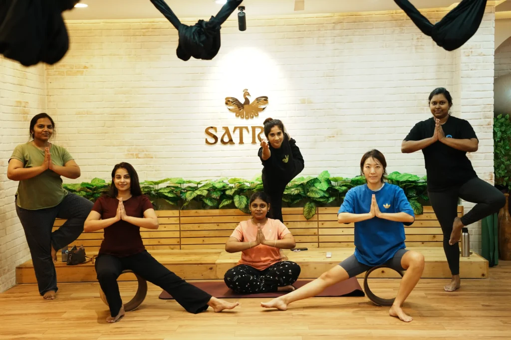 Women practicing yoga poses together at Satria Studio